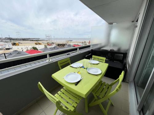 une table et des chaises vertes sur un balcon avec vue sur l'aéroport dans l'établissement Résidence Les Marines - PORNICHET APAPRTEMENT FACE MER MAE-8801, à Pornichet