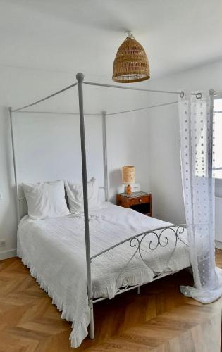 a bedroom with a white bed with a metal canopy at Les étoiles de Germaine in Lavit