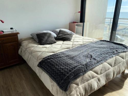 - un lit avec une couverture grise et des oreillers dans l'établissement Résidence L'amiral B - Location de Vacances - PORNICHET -APPARTEMENT FACE MER MAE-1801, à Pornichet