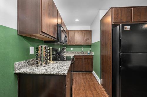 a kitchen with wooden cabinets and a black refrigerator at Modern Quirky Apartment Near Medical Center in Houston