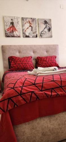 a bedroom with a red bed with four pictures on the wall at Antonio Apartments in Ohrid