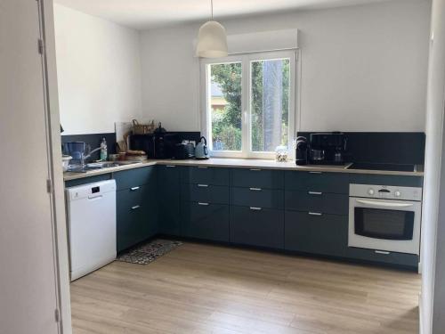 une cuisine avec des armoires bleu foncé et une fenêtre dans l'établissement Résidence Arm-54-pornichet - PORNICHET - SAINTE MARGUERITE - MOULIN D'ARGENT MAE-3571, à Pornichet
