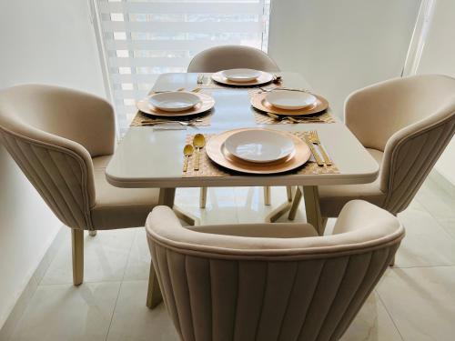 a dining room table with chairs and plates on it at Apartamento Marbella Piso 28 - Playa in Cartagena de Indias