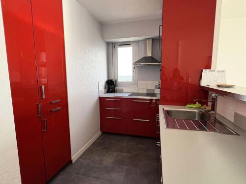 une petite cuisine avec des armoires rouges et un évier dans l'établissement Résidence La Louisiane - LA BAULE - IMMEUBLE EN VAGUES - FACE MER MAE-5181, à Mazy