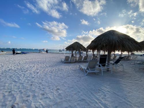 a group of chairs and straw umbrellas on a beach at paradise close to the beach pool free parking,wifi- punta cana in Punta Cana