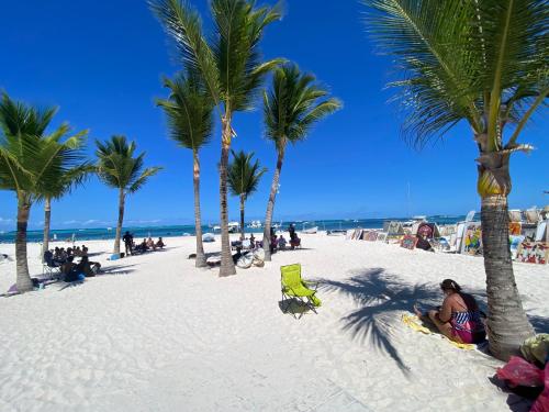 a beach with palm trees and people sitting on the sand at paradise close to the beach pool free parking,wifi- punta cana in Punta Cana