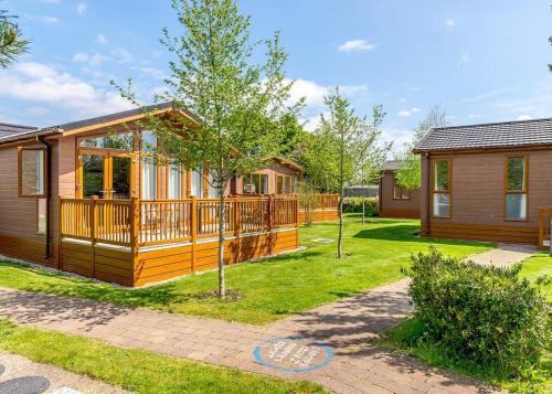 a log cabin with a deck and a yard at Canterbury Reach Lodge Retreat in Kent