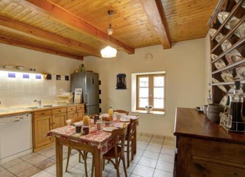 une cuisine avec une table et des chaises dans une cuisine dans l'établissement La Fenière, à Merle-Leignec