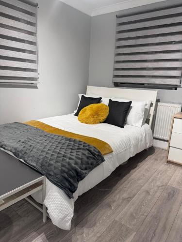 a bedroom with a white bed with a yellow pillow at Stylish 2-Bed Garden Flat, 5 Mins to Brixton in London