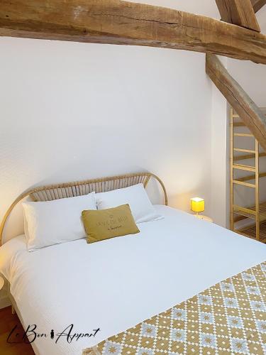 - une chambre avec un lit blanc et un livre dans l'établissement Le Bon'Appart au Cœur de Saumur, à Saumur