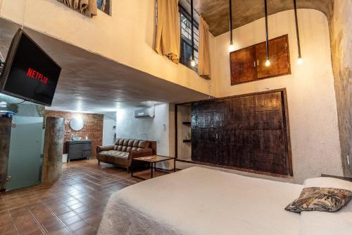 a room with a bed and a couch and a tv at Suite Subterránea con AC, de 2 Niveles Chapalita 6 in Guadalajara