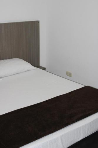 a bedroom with a bed with white sheets and a brown blanket at Hotel San Cayetano in Ocaña