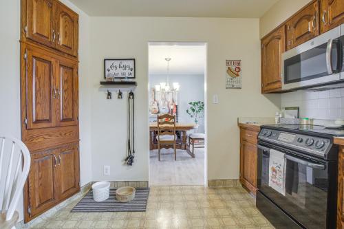 a kitchen with wooden cabinets and a dining room at Walk to Lake Family Getaway with Yard in Menasha! in Menasha