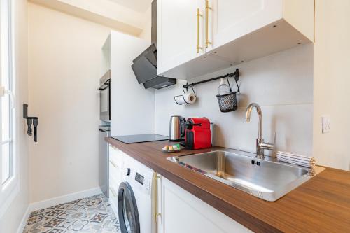 une petite cuisine avec un évier et une machine à laver dans l'établissement Plein Centre Enghien Les Bains 10 min de Paris, à Enghien-les-Bains