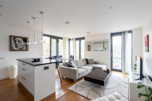 a kitchen and living room with a couch and a table at Modern, fully furnished apartment with ensuite, private balcony and elevator in Notting Hill in London