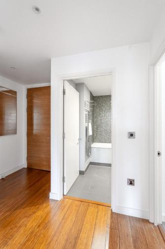 an empty living room with white walls and wood floors at Modern, fully furnished apartment with ensuite, private balcony and elevator in Notting Hill in London