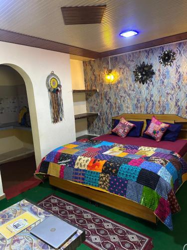 a bedroom with a colorful bed with a laptop on it at Laxmi Narayan Homestay-Harshil in Harsil