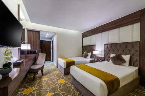 ein Hotelzimmer mit zwei Betten und einem Schreibtisch in der Unterkunft Abha Gardn Millennium Hotel in Abha