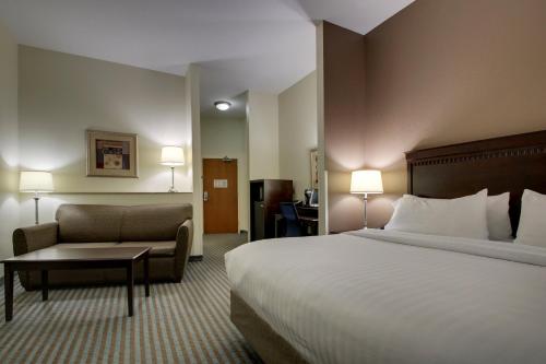 a hotel room with a large bed and a couch at Holiday Inn Express Leland - Wilmington Area by IHG in Leland