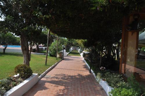 a red brick sidewalk next to a building with trees at Hotel Savoia in Procida