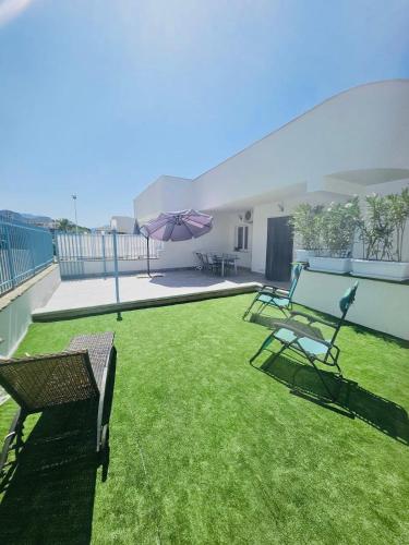 a lawn with chairs and an umbrella on a balcony at DV holiday home in Isola delle Femmine