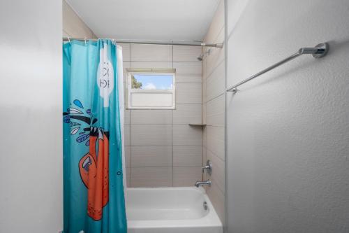 a bathroom with a blue shower curtain and a bath tub at Bright and Cozy Med Center Apartment in Houston
