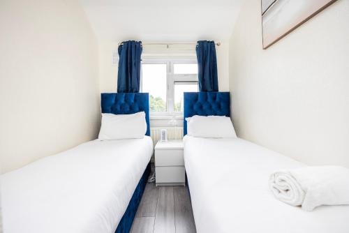 two beds in a small room with blue curtains at Garland Modern Close To Station 3 Bedroom City Apartment in London