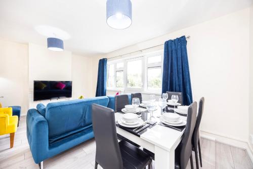 a dining room with a blue couch and a table and chairs at Garland Modern Close To Station 3 Bedroom City Apartment in London