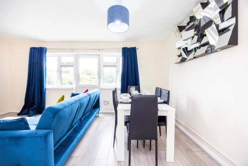 a living room with a table and a blue couch at Garland Modern Close To Station 3 Bedroom City Apartment in London