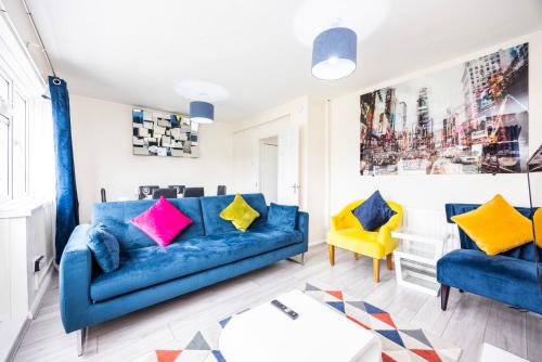 a living room with a blue couch and yellow chairs at Garland Modern Close To Station 3 Bedroom City Apartment in London