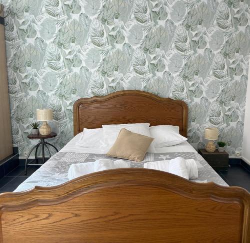 een slaapkamer met een houten bed met bloemenbehang bij Gîte Petite Palette in Ribeauvillé