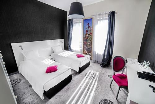 a bedroom with two beds with pink pillows and a desk at Lawendowe Termy in Uniejow