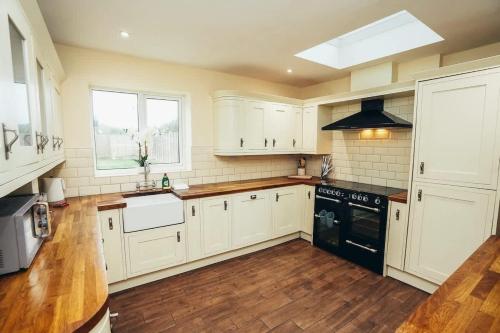 a kitchen with white cabinets and a black appliance at Huge 4 Bed Family Home in Derbyshire with Parking in Derby