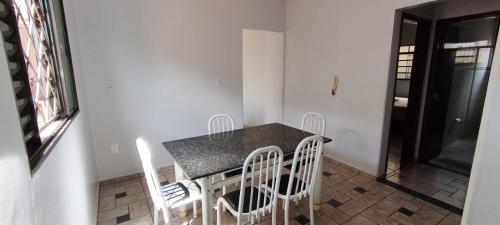 een eettafel met witte stoelen en een aanrechtblad bij Casa para tecnoshow 2025 rioverde in Rio Verde