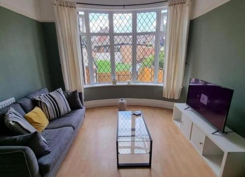 a living room with a couch and a tv at Near city centre sleeps 11, 4-spacious Bed rooms,2-Lounges 2-toilets 1-kitchen ideal Familys&Groups in Manchester