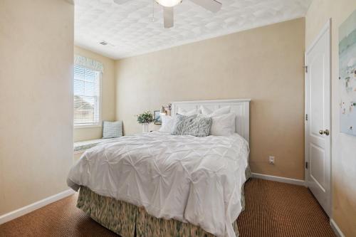 a bedroom with a bed with a white comforter and a window at Golf Tennis Pool Beach - Bay Creek Caddy Shack in Cape Charles