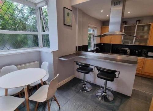 a kitchen with a table and chairs and a counter at Near city centre sleeps 11, 4-spacious Bed rooms,2-Lounges 2-toilets 1-kitchen ideal Familys&Groups in Manchester