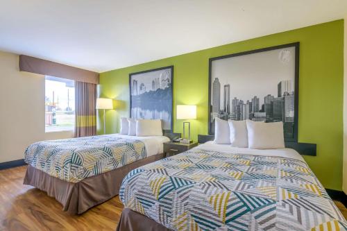 two beds in a hotel room with green walls at Motel 6 Forsyth, GA Tift College in Forsyth