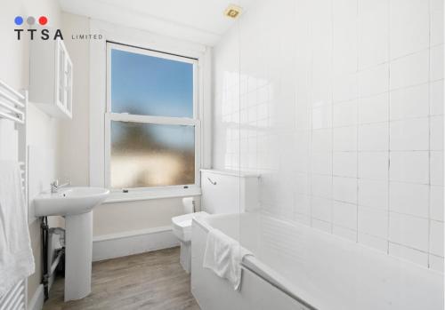ein weißes Badezimmer mit Badewanne und Waschbecken in der Unterkunft 1-Bedroom Apartment near East Croydon Station - 2 in South Norwood