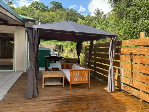 a black umbrella on a deck with a bench and a table at Villa Massy in Rivière-Salée