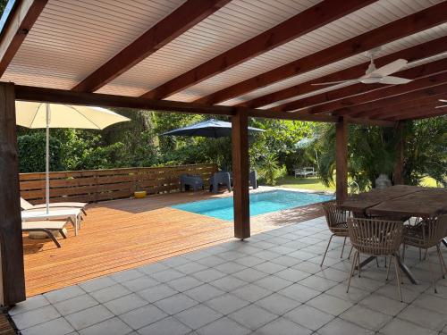 a wooden deck with a table and chairs and an umbrella at Villa Massy in Rivière-Salée