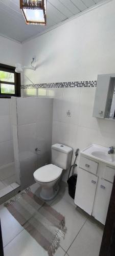 a white bathroom with a toilet and a sink at Villa Golfinho in Arraial d'Ajuda