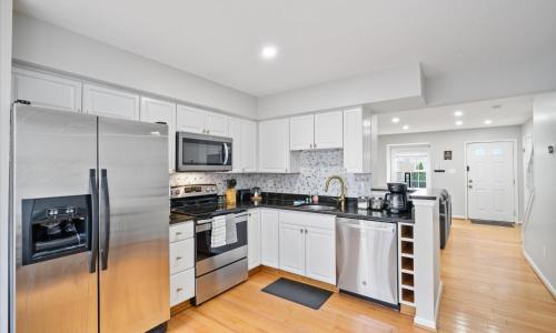a kitchen with white cabinets and a stainless steel refrigerator at Modern Luxury DC Free Parking in Arlington