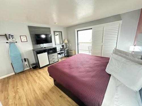 a bedroom with a bed with a red bedspread at Ocean Gate Inn in Santa Cruz