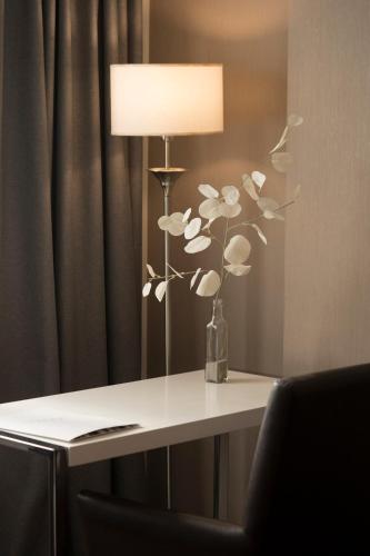 a table with a lamp and a vase of flowers on it at Hotel Tolosa in Puerto Madryn