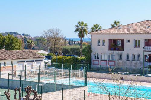 un court de tennis en face d'une piscine dans l'établissement Le Cali, Terrase, Parking, Piscine, Clim, à Villeneuve-Loubet