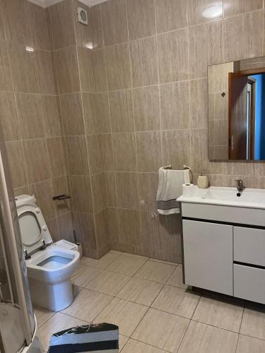 a bathroom with a toilet and a sink and a mirror at Hostel das Flores in Senhora da Hora