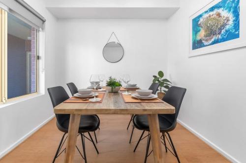 a dining room with a wooden table and chairs at City Haven Modern 2BR Apartment on Carrington St in Adelaide