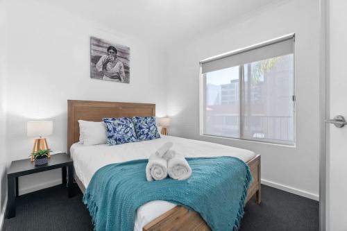 a bedroom with a bed with two towels on it at City Haven Modern 2BR Apartment on Carrington St in Adelaide