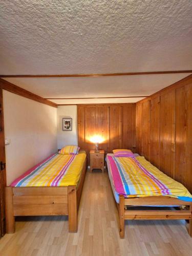 two beds in a room with wooden walls at Apartments Saba & Jona in Uetendorf